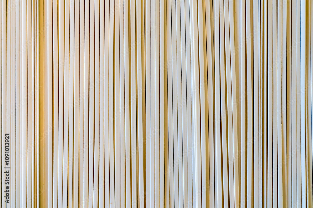 Fototapeta premium Close-up of vertical udon noodle, wooden sticks in parallel arrangement. Textured abstract pattern. Neutral background for design.
