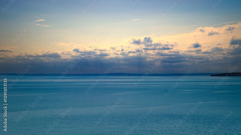 Obraz premium Tranquil seascape under a clear sky. The water reflects gentle clouds