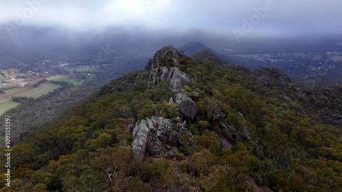Aerial footage of Grampians National Park at dawn, gliding through the mountain forests, revealing majestic natural rock formations, peaks, and valley landscapes