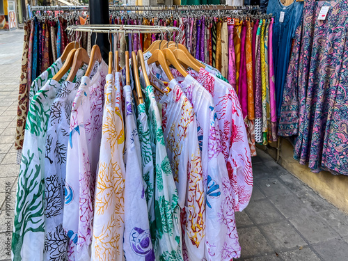 Colorful clothing items such as scarves, shawls, skirts, blouses, blankets and others, displayed on hangers in front of shops as a background. Nicosia, Cyprus photo