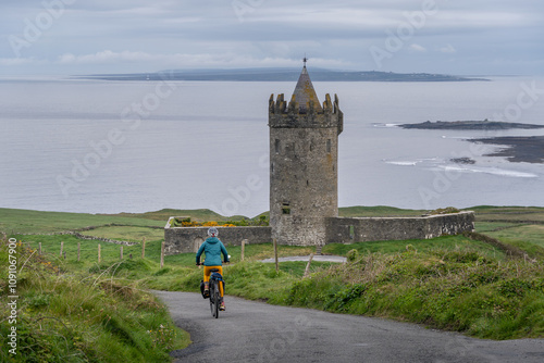Cycling through the Irish countryside, cycling along the Wild Atlantic Way, Doonagore Castle Tower, Doolin, County Clare, Ireland.
