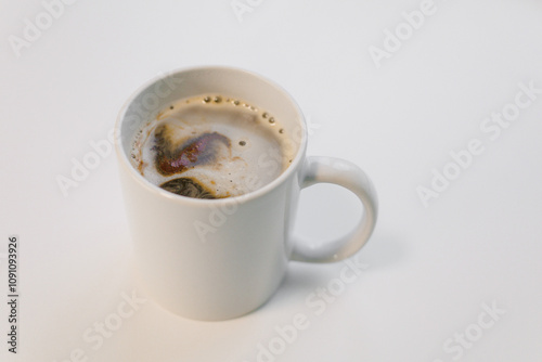A ceramic coffee cup filled with dark brew sits on a plain white table, inviting a moment of relaxation and comfort in the morning light