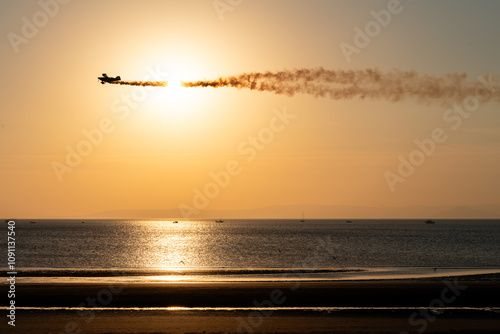 The sun sets over Ayr beach, and the silhouette of a flying aerobatic plane is visible in the sky. Which took part in the Ayr Show in the city of Ayr, Scotland, 06 09 2024 photo