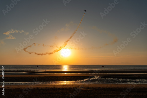 The sun sets over Ayr beach, and the silhouette of a flying aerobatic plane is visible in the sky. Which took part in the Ayr Show in the city of Ayr, Scotland, 06 09 2024 photo