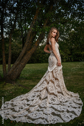 A young girl poses in a boho wedding dress, cowboy boots, a cowboy hat, and a denim jacket.