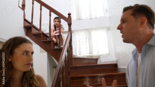 Stressed and unhappy young girl watch her parent arguing from the stair. Domestic violence at home and traumatic childhood develop to depression and anxiety. Unhealthy family concept. Synchronos photo