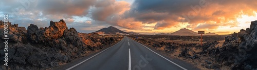 Serene Road Through Breathtaking Lava Fields Under Dramatic Sky at Sunset With Majestic Mountains in the Background, Perfect for Travel and Nature Themes photo