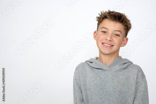 cool young 12 year old boy with grey hoody sweater posing in front of white background, having fun