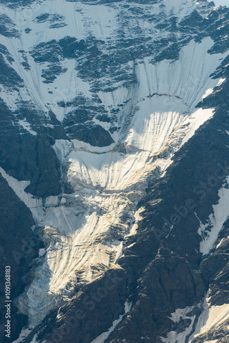 A stark view of a massive glacier sliding down a rocky mountainside. Caucasus Mountains photo