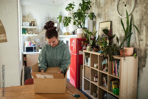 Young woman opening package in cardboard box at home