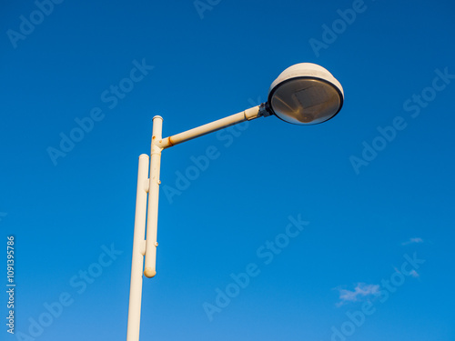 Vintage White Lamp Post with Minimalist Design Against a Clear Blue Sky