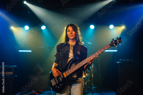 Female musician playing bass guitar on stage during concert