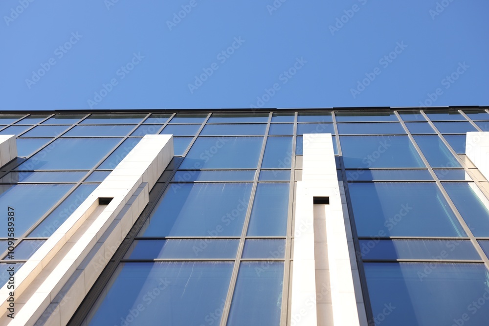 Fototapeta premium Exterior of modern building with many windows against light blue sky, low angle view