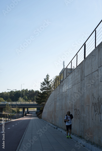 photo Urban pedestrian area with graffiti walls, walking path, and overpass under clear sky suggests dynamic city lifestyle and outdoor activities photo