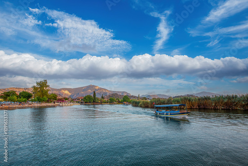 Obraz na płótnie The rock-cut temple tombs of the ancient city of Kaunos in Dalyan, Muğla, Turkey. Beautiful view of Dalyan river with reed beds, excursion boats and carved tombs in the background. w salonie