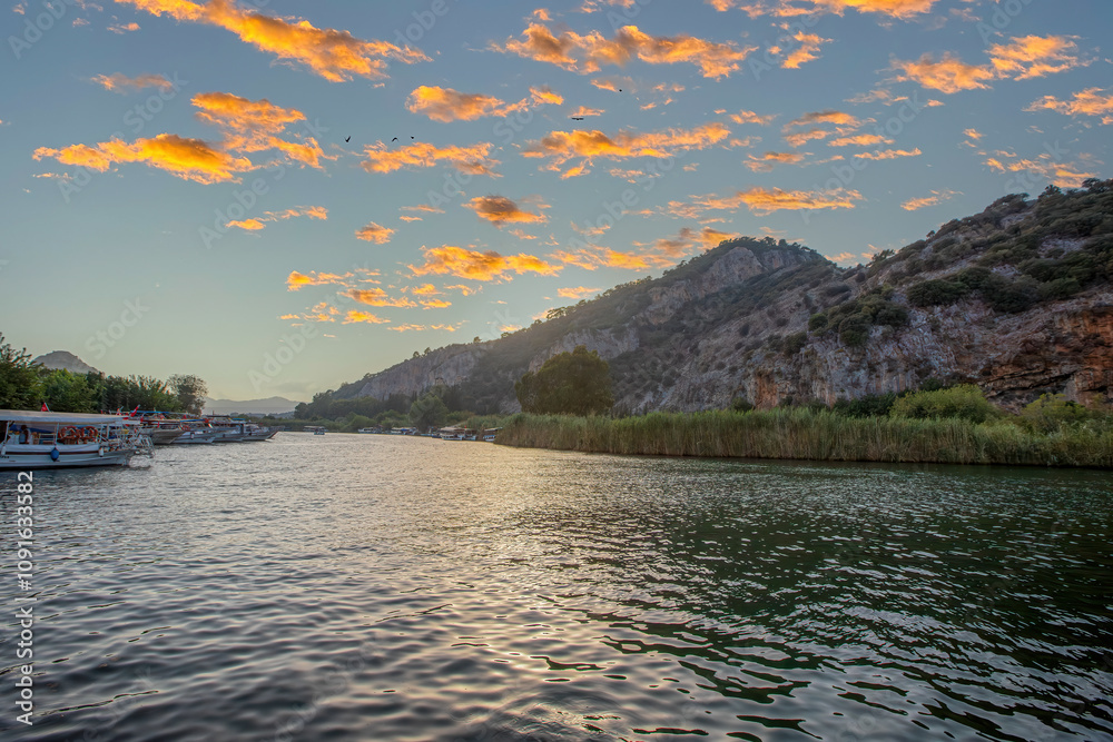 The rock-cut temple tombs of the ancient city of Kaunos in Dalyan, Muğla, Turkey. Beautiful view of Dalyan river with reed beds, excursion boats and carved tombs in the background.