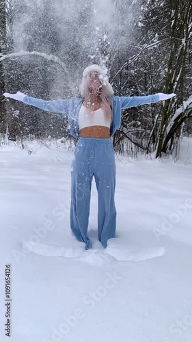 Beautiful sexy girl in a blue suit and top, in the forest in winter, throwing up snow, slow motion.