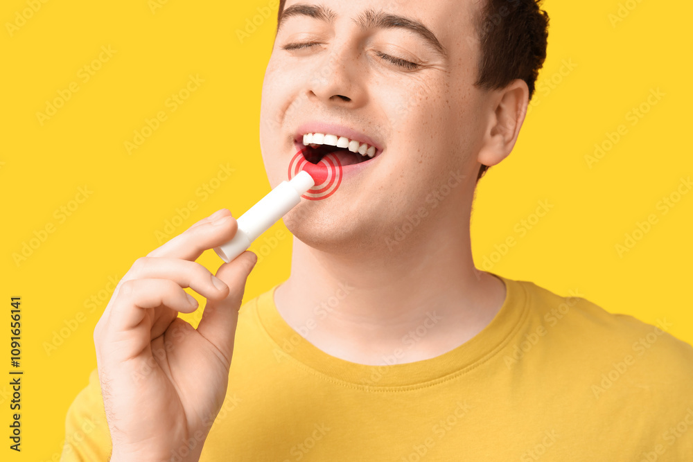 Handsome young man applying lip balm on yellow background Handsome young man applying lip balm on yellow background