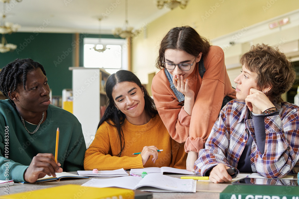 Fototapeta premium Group of students spending time together in classroom, engaged in collaborative studying. Each student deeply involved in work, wearing casual attire, creating lively, friendly atmosphere