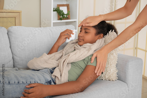 Mother taking care of her ill African-American daughter with tissue at home