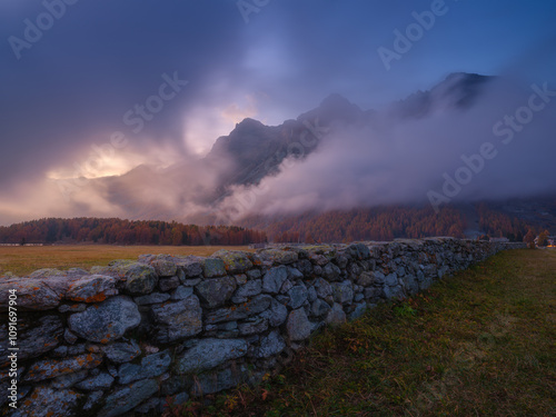 Mountain landscape at dawn. Sunbeams in a valley. Foggy weather in the mounta...