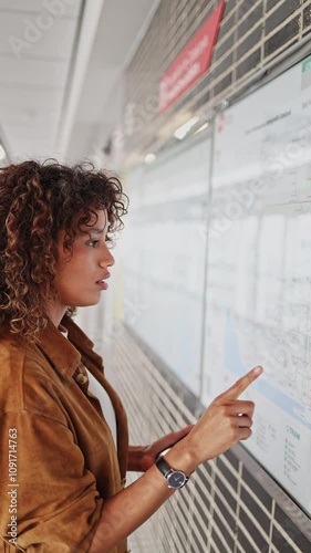 Young woman tracing a subway map while deciding on her travel destination in an urban environment.   Tourist studying subway map deciding destination