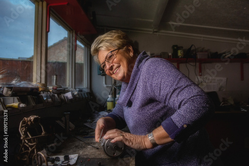 A mature woman restoring a vintage motorcycle in a garden shed workshop.
