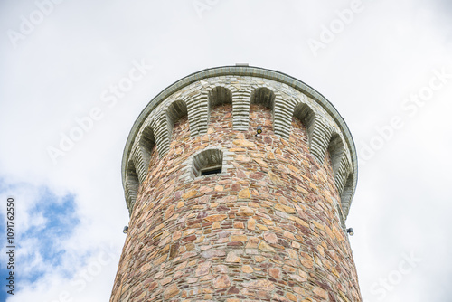 The Dalimil Lookout Tower rises on Vetrov Hill, showcasing its stone structure against a cloudy sky. This replica honors the original lookout tower once found on Kralicky Sneznik.