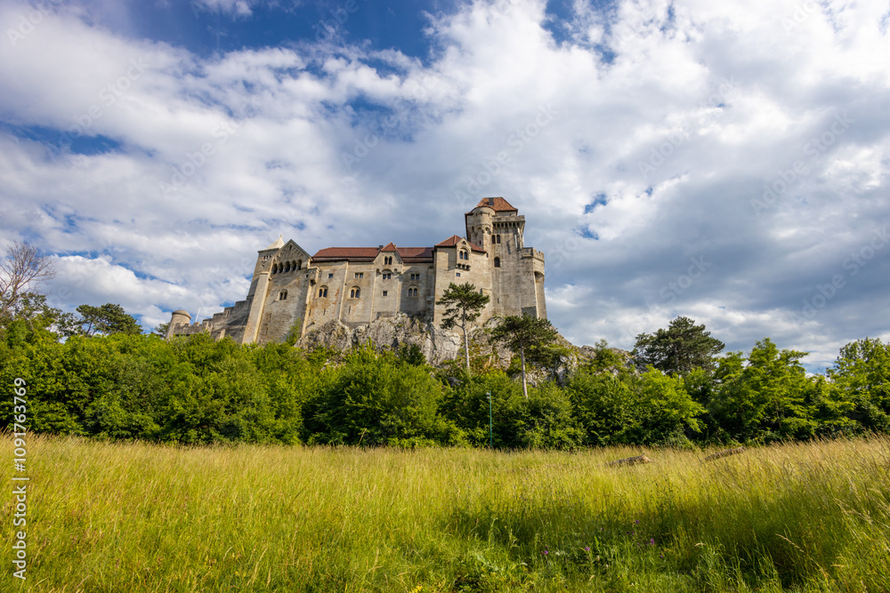 Fototapeta premium Ancient castles architecture in Europe. Austria medieval citadel made of bricks. Rocky walls of an old historical castle with towers and bridge on a sunny summer day, European landmark and history