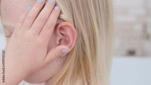 Young girl touching her ear repeatedly indicates ear pain and discomfort, highlighting a common childhood ailment