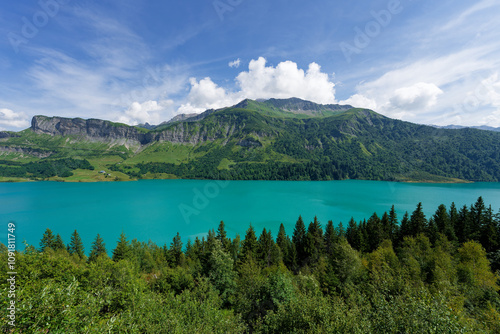 Lac de Beaufort prise au grand angle avec eau d'un bleu turquoise entouré de sapins 