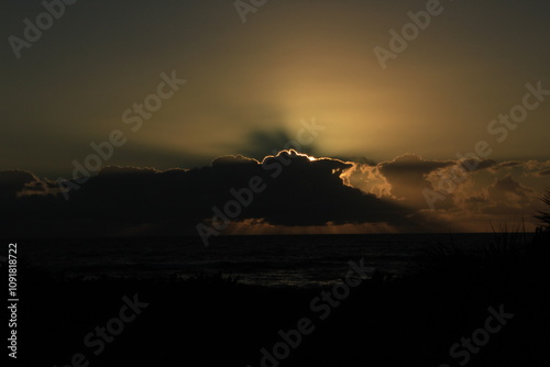 sunrise over sea with sun rays behind illuminated cloud