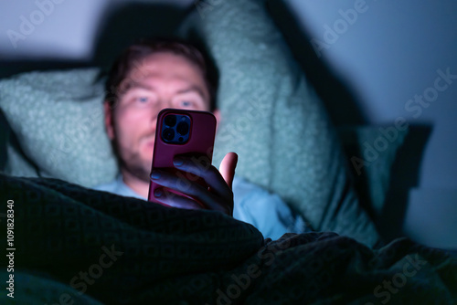 man with phone in bed in the dark, using phone before sleep