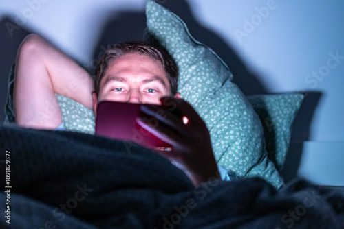 man with phone in bed in the dark, using phone before sleep, using phone before sleep. phone device addiction, screen time	