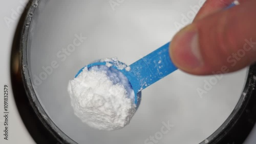 Close up of a hand scooping creatine with a scoop