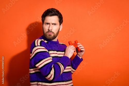 Photo portrait of nice young male suspicious spy binoculars wear trendy striped violet outfit isolated on orange color background photo