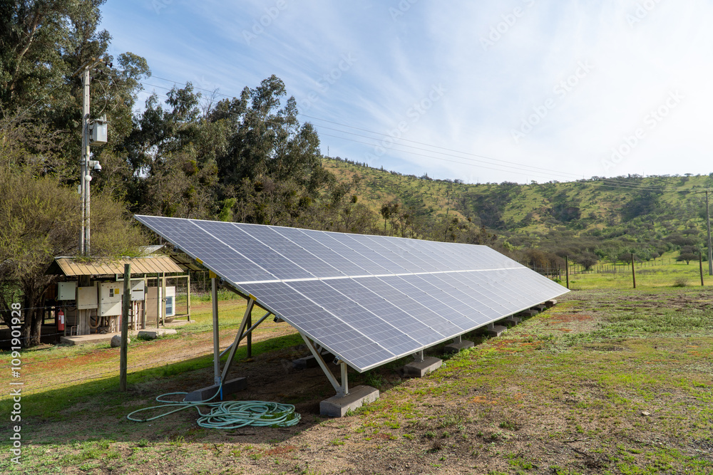 A wide view of solar panels installed in a green field under a clear blue sky. The panels align in rows, capturing sunlight amidst the natural beauty of the landscape.
