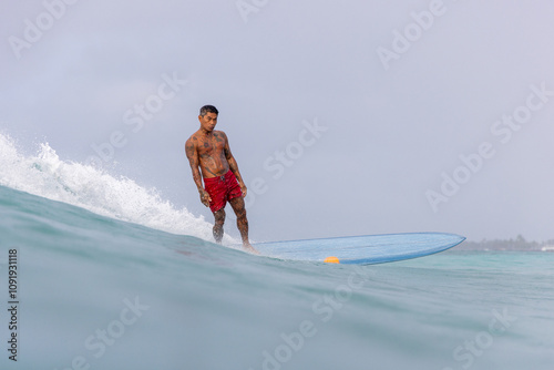 Photography A man in a red swimsuit is surfing a wave on a blue surfboard