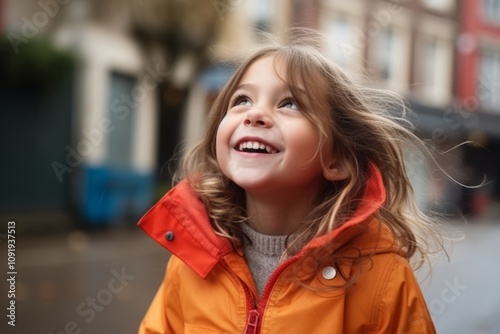 Portrait of a cute little girl in an orange jacket on the street