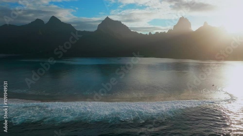 Morning sunrise blue sky sun flare Moorea island Cooks Opunohu bay French Polynesia aerial drone lagoon coral reef Mount Mauaroa Tohivea Rotui jagged peaks Haapiti Paopao Pacific Ocean upwards photo