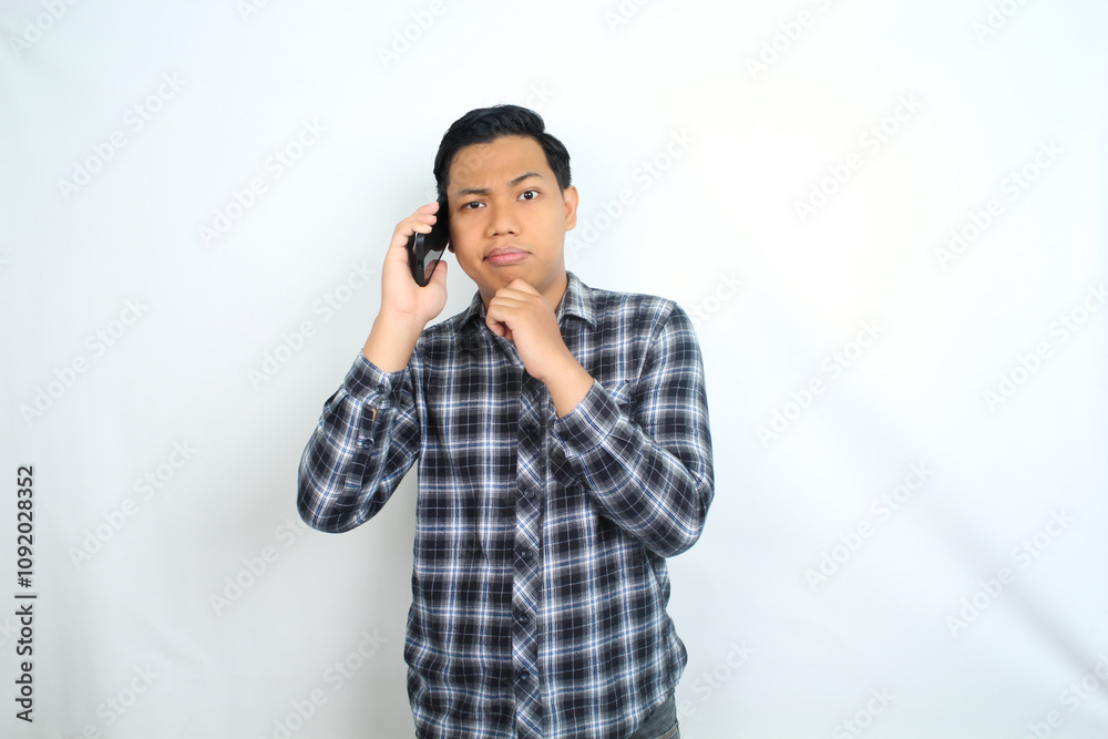 © M Alfan Setyawan - clueless asian man talking on smartphone with confused face expression isolated on white background