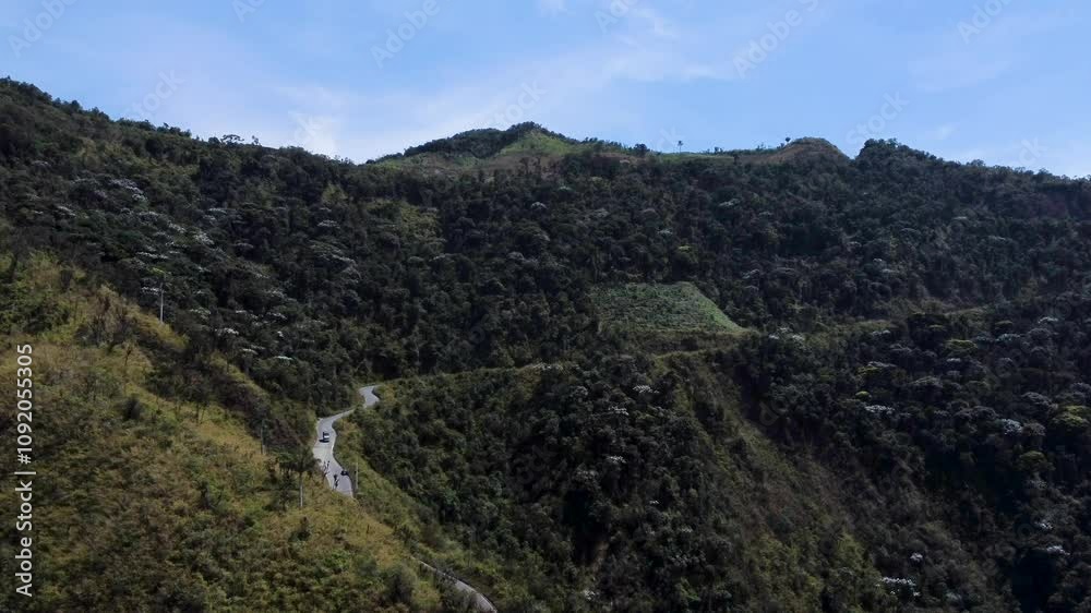 Aerial along lush green mountainside with curvy road, cars driving in mountain range between Guaranda and Montalvo, Bolivar Province, Ecuador Aerial along lush green mountainside with curvy road, cars driving in mountain range between Guaranda and Montalvo, Bolivar Province, Ecuador