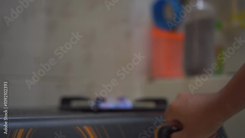 Man hand turning on the kitchen gas stove for cooking food. Gas stove with blue color flame.
