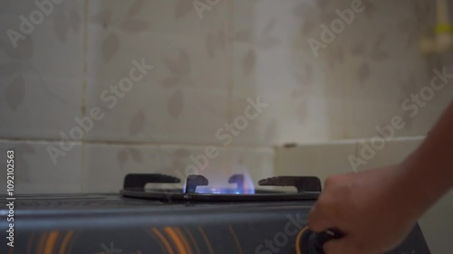 Man hand turning on the kitchen gas stove for cooking food. Gas stove with blue color flame.