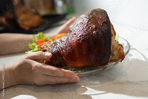 A person is holding a deliciouslooking piece of meat on a large, white plate, showcasing a wellprepared dish for a meal photo