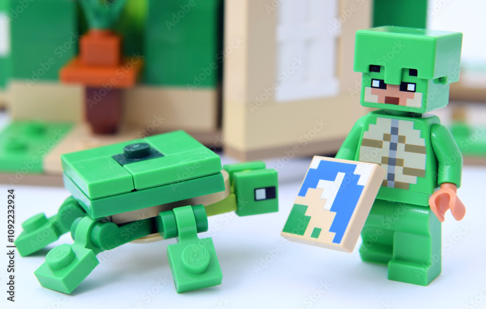 Naklejka premium Lego minifigure of popular game Minecraft with pixel map are showing to turtle. Editorial illustrative image of popular plastic toys.