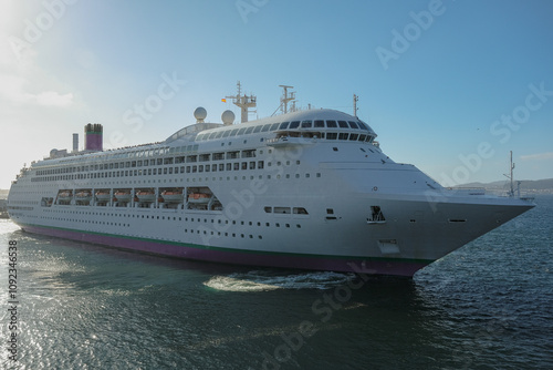 Classic cruiseship cruise ship liner Ambience sail away departure from Vigo port, Spain in Galicia during summer Atlantic Coast cruising with blue sky and coast line