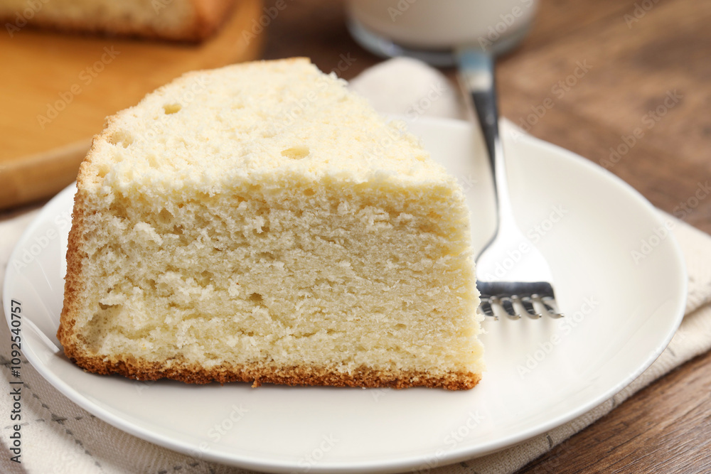 Piece of delicious sponge cake and fork on wooden table, closeup Piece of delicious sponge cake and fork on wooden table, closeup