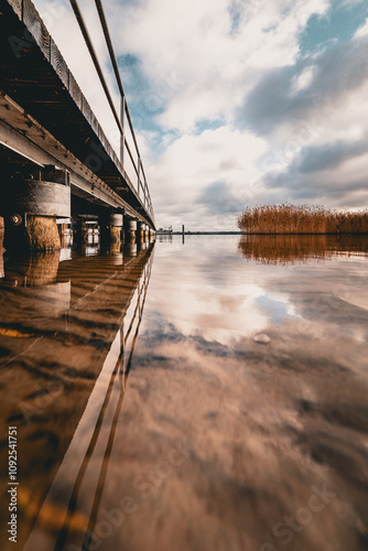 Steg aus niedriger Perspektive mit symmetrischer Spiegelung im ruhigen Wasser photo