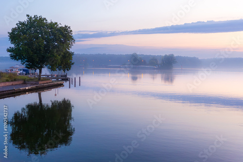 Stiller See im Morgengrauen mit Bäumen und sanften Farben